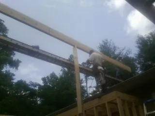 Carpenter setting a ridge beam over a new addition frame — Ice Dam Removal by Roofing Brothers in New Market